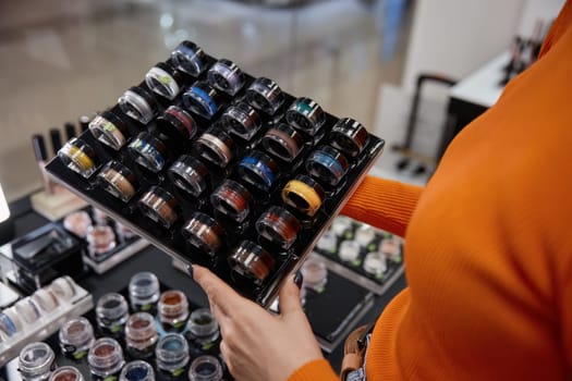 Woman in cosmetics shop holding colorful eye shadow set. Bright cosmetics for eyes, make-up time