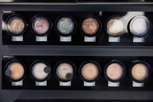 Top view of pearlescent eye shadows in cosmetics shop. Colorful bright decorative products for face