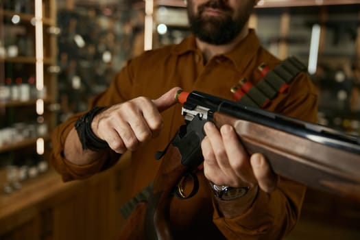 Shopping at legal commercial weapon store for hunting hobby. Man loading bullet into the rifle closeup. Selective focus on gun barrel and bullet
