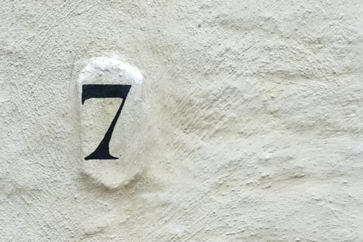 House number 7 on the facade of an old house in the old town of Bruges in Belgium. Text space on the right side.
