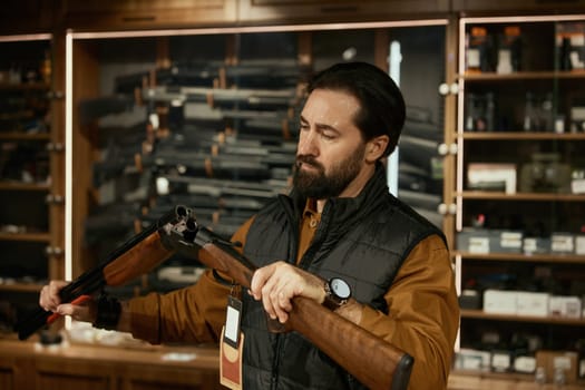 Concentrated salesman checking gun firearm while working at weapon hunter shop. Small business owner providing merchandising and firearm goods inspection