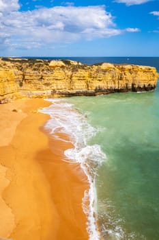 Vertical view over cliffs and ocean waves crashing onto Praia da Ponta Pequena beach near Albufeira, Algarve, Portugal