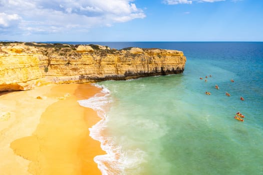 View of cliffs and canoes on ocean, Praia da Ponta Pequena beach near Albufeira in Portugal