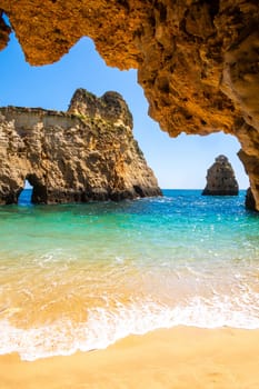 Small, heavenly and difficult to access beach vertically photographed from inside the rocks, near Portimao in the Algarve region of Portugal