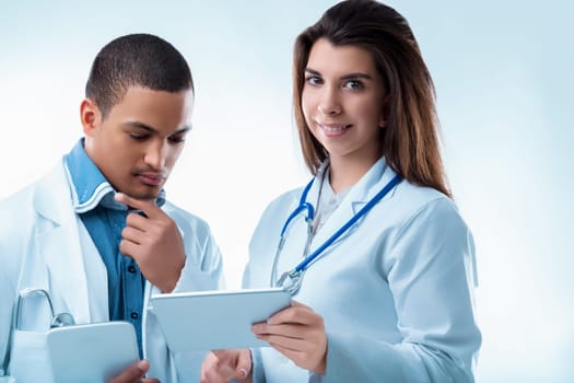 Two healthcare professionals discuss a patient's report on a tablet, showing teamwork and compassion in a hospital