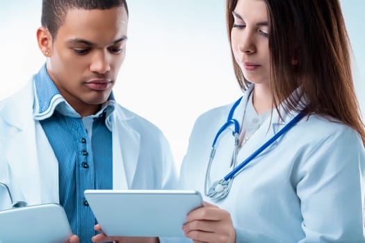 Two doctors are reviewing patient information on a digital tablet, showcasing the use of technology in modern healthcare. They are working together, sharing their knowledge and expertise