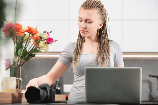 Woman photographer prepares her camera and laptop in a bright kitchen, blending technology with her passion for photography
