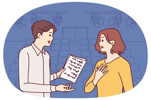 Man and woman working as actors are rehearsing theatrical performance standing on stage. Guy and girl are memorizing text of theatrical performance, wanting to receive award for acting