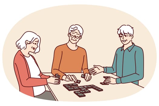 Elderly people play dominoes undergoing rehab at nursing home or having sunday get-together with friends. Men and women are sitting at table enjoying game of dominoes with former colleagues