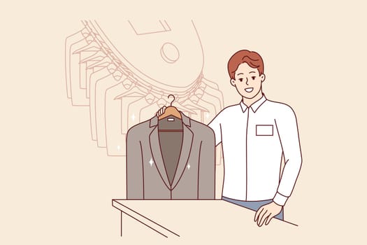 Man working in dry cleaner shows business jacket, cleaned of stains from food or sauce. Dry cleaner manager smiles, inviting to become client and take advantage of services for caring for clothes