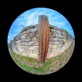 Old wooden post and ancient stone wall exterior with fish-eye distortion