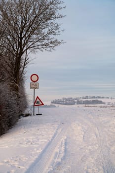 Road through a snow covered forest, slippery and frosty street in winter, empty highway in cold temperature, seasonal weather and landscape