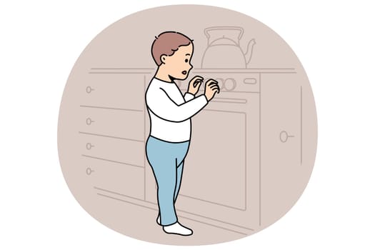 Little boy plays with gas stove and touches dangerous kitchen equipment while parents are away. Curious child toddler studies stove with interest and needs supervision to avoid accident
