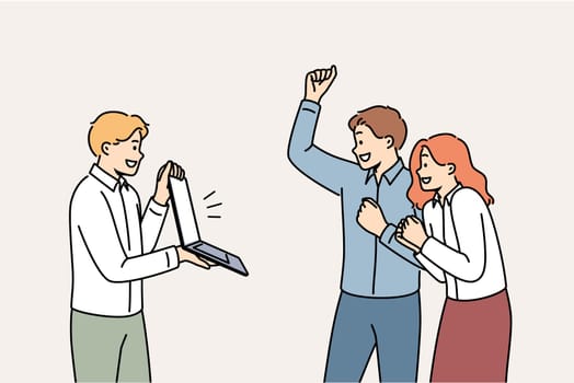 Overjoyed team of business people motivated for success looks at laptop and celebrates excellent result. Manager shows computer to two clerks rejoicing over fulfillment of corporation business kpis