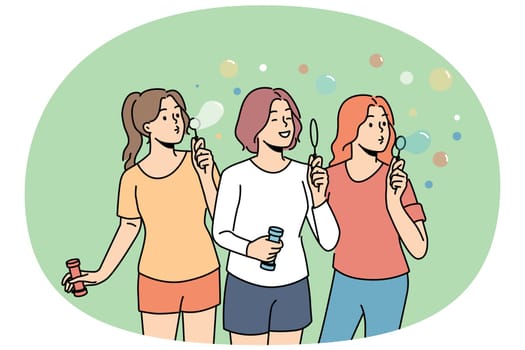 Teenage girls inflate soap bubbles enjoying outdoor recreation in hot summer weather. Three high school girls love to hang out and have fun playing in park, for concept of carefree childhood