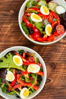 Delicious salad of fresh vegetables and quail eggs in plate. Fresh salad bowl.