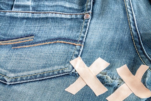 Ripped blue jeans below the back pockets. Selective focus with shallow depth of field.