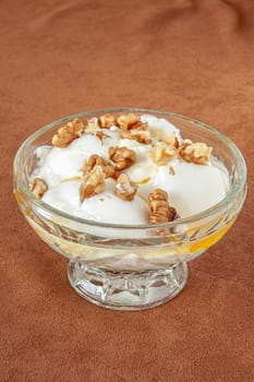 Yogurt dessert with honey and walnuts in a glass bowl. Selective focus with shallow depth of field.