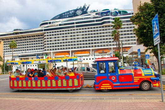 Sicily, Messina, Italy - 26 Sep 2023. A train takes tourist at port of Messina on Sizilia for city tour. The cruise ship Msc World Europa in background.