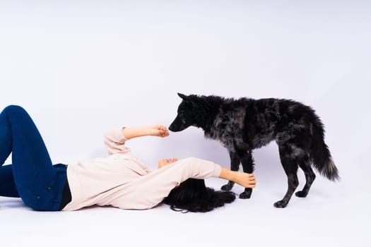 Happy brunette lady in a casual wear hugging mudi pet dog, studio background.
