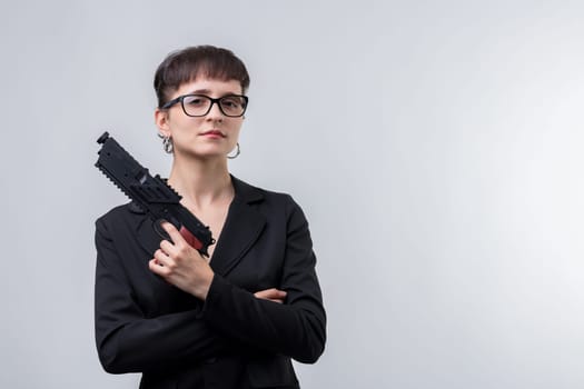 Businesswoman wearing a black suit and glasses is holding a gun with her arms crossed, looking confident and powerful