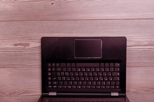 Laptop with a blank screen is lying on a wooden desk, inviting viewers to consider the possibilities and challenges of working remotely