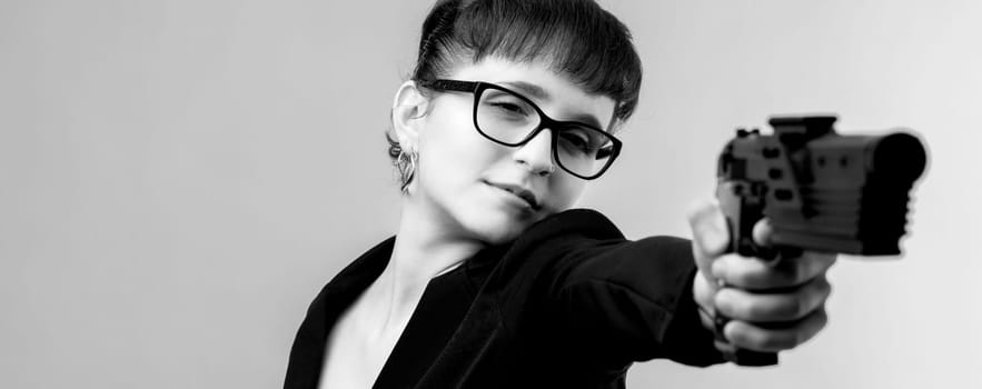 Determined young woman in business attire aims a handgun in this intense black and white portrait, embodying themes of self defense and empowerment. Perfect for conveying strength and resilience
