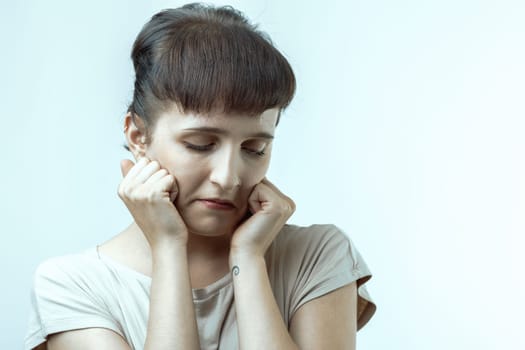 Young woman holds her head in her hands, showing deep sadness and loneliness. She looks overwhelmed by negative emotions like despair and grief, reflecting inner turmoil