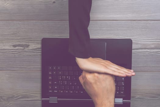 woman's hand blocks a metaphorical male hand emerging from a laptop, symbolizing her defense against cyber threats and online abuse. This highlights the struggle against digital harassment