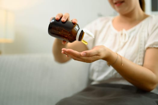 Close up shot of middle aged woman taking fish oil supplements for health and wellness.