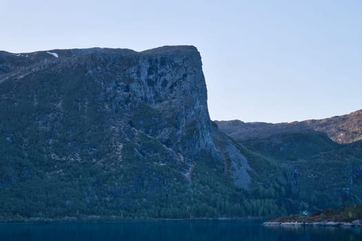 Norwegian fjord landscape. View of mountains with rugged vegetation. Crystal clear water in the foreground. Landscape from Scandinavia
