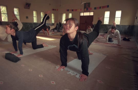 People at a Yoga class at the Holy Ganges River in the city of Rishikesh in the Province Uttarakhand in India.  India, Rishikesh, February, 1998