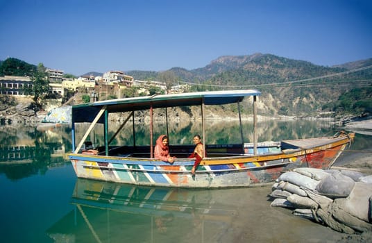 a Tour Boat on the Holy Ganges River with the city of Rishikesh in the Province Uttarakhand in India.  India, Rishikesh, February, 1998