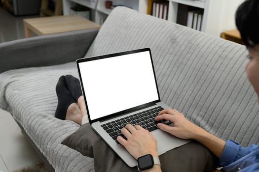 Man hands using laptop with blank screen on sofa at his living room.