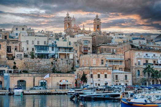 Medieval Malta: Birgu and Vittoriosa waterfront, Malta, features iconic churches, historic buildings and luxury yachts in Malta. Sunset in city. Cultural heritage of Malta