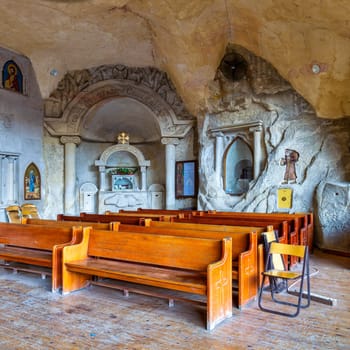 The interior of the St. Simon the Tanner Cathedral in Cairo, Egypt, featuring a carved stone niche including the remains of st. Simon's body and pews in a cave-like space
