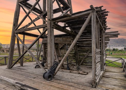 A close-up view of the worlds first industrially drilled oil well in Baku, Azerbaijan. The wooden structure of the well is visible, along with a glimpse of the city skyline in the background