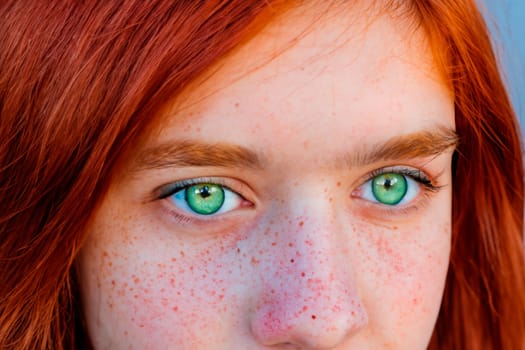 Close-up portrait of teenage girl with red head and green eyes.