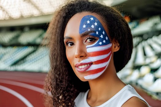 Female fan of the US national team spectator at the stadium with the painted american flag on her face.