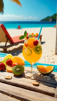 glass of refreshing drink with slices of fruit and decoration on a wooden beach table close-up, next to a sun lounger on a sandy beach, beautiful tropical beach in the background, sea, warm sunny day on a trip.