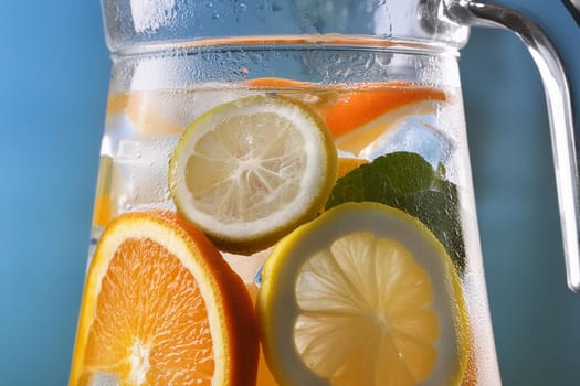 Close-up of a refreshing fruit-infused water pitcher with ice cubes and slices of citrus fruits.