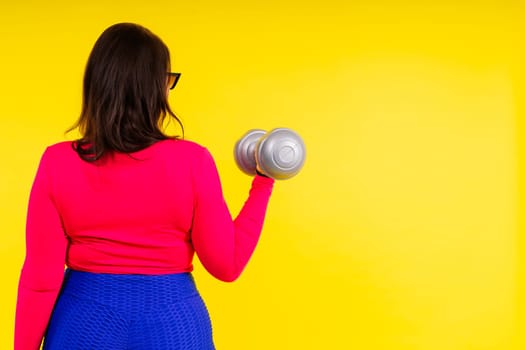Sporty model with curvy figure with a dumbbells. Dynamic movement. Motivation and healthy lifestyle
