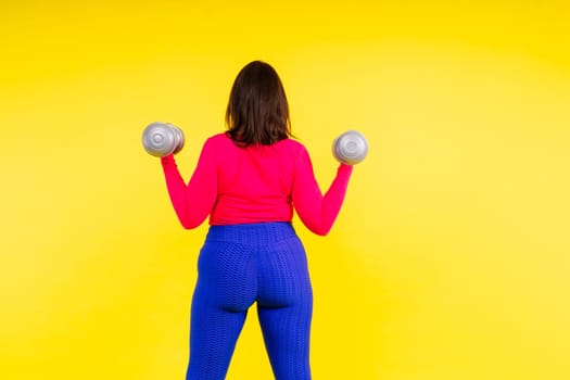 Sporty model with curvy figure with a dumbbells. Dynamic movement. Motivation and healthy lifestyle