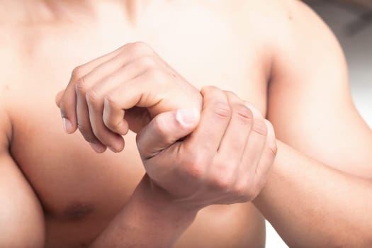 man grips his wrist with the other hand, indicating possible wrist pain or tendonitis due to repetitive movements. The close-up emphasizes the tension in his grip and the focus on the wrist