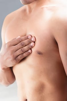 man's hand is pressed against his chest, indicating chest or intercostal pain. His lips are slightly pursed, and the background is blurry, drawing attention to the point of contact