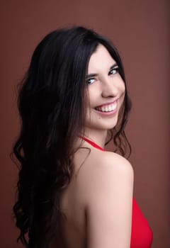 Beautiful young woman in a red gown smiles confidently, radiating happiness and positivity. Perfect for fashion and beauty ads, social media, or dating apps