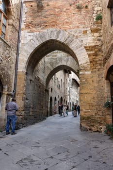 San Gimignano, Italy - Sept 17, 2022: Tourists on Via San Mateo in the medieval town of San Gimingnano. Tuscany, Italy