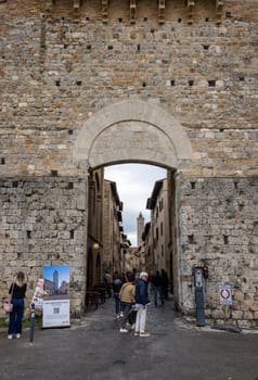 San Gimignano, Italy - Sept 17, 2022: Tourists entering the historic center of San Gimignano via the Porta di San Giovanni. Tuscany, Italy