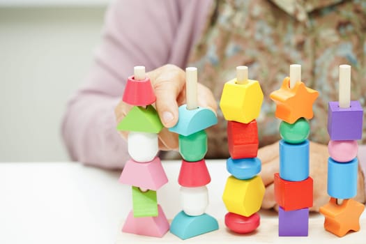 Asian elderly woman playing puzzles game for treatment dementia prevention and Alzheimer disease.