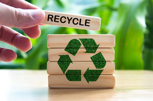 Hand placing wooden block with text recycle. Recycle concept with recycle symbol.